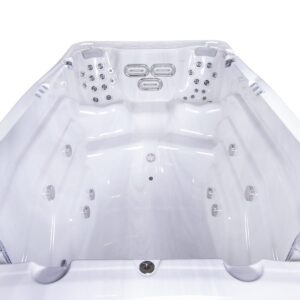 Empty white jacuzzi tub with numerous chrome jets and ergonomic seating, viewed from the open end, ready for use.